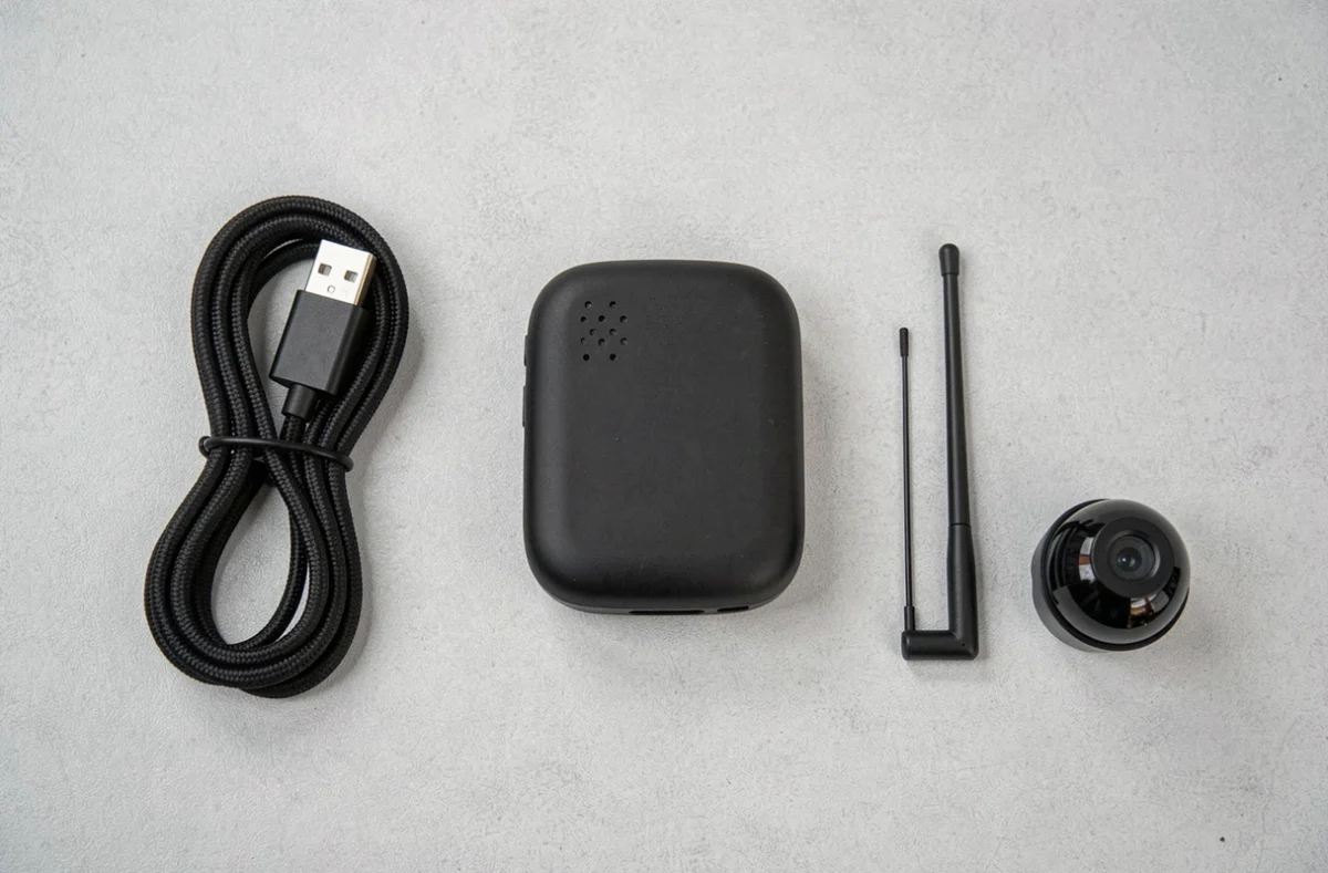Vue aérienne d'un détecteur de traceur GPS et caméra espion avec ses accessoires sur fond neutre