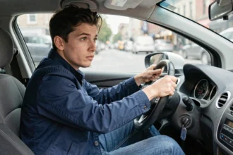 Jeune conducteur masculin au volant d'une voiture compacte, représentant la surprime d'assurance jeune conducteur
