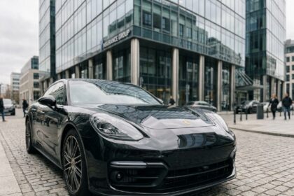 Porsche Panamera noire garée devant une agence d'assurance moderne en milieu urbain