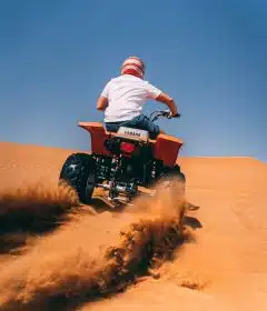 person riding ATV on desert during daytime