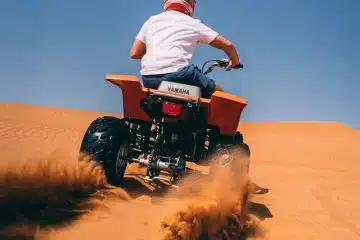 person riding ATV on desert during daytime