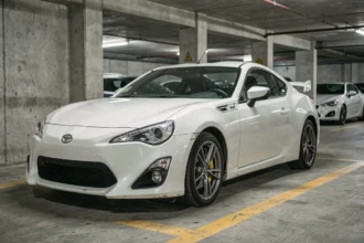Toyota 86 blanche garée dans un parking souterrain, vue avant trois quarts basse angle, détails carrosserie et jantes visibles
